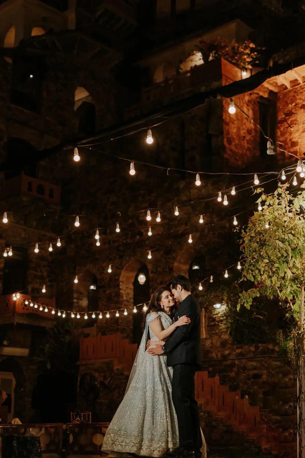 Couple sharing a moment beneath strings of evening lights