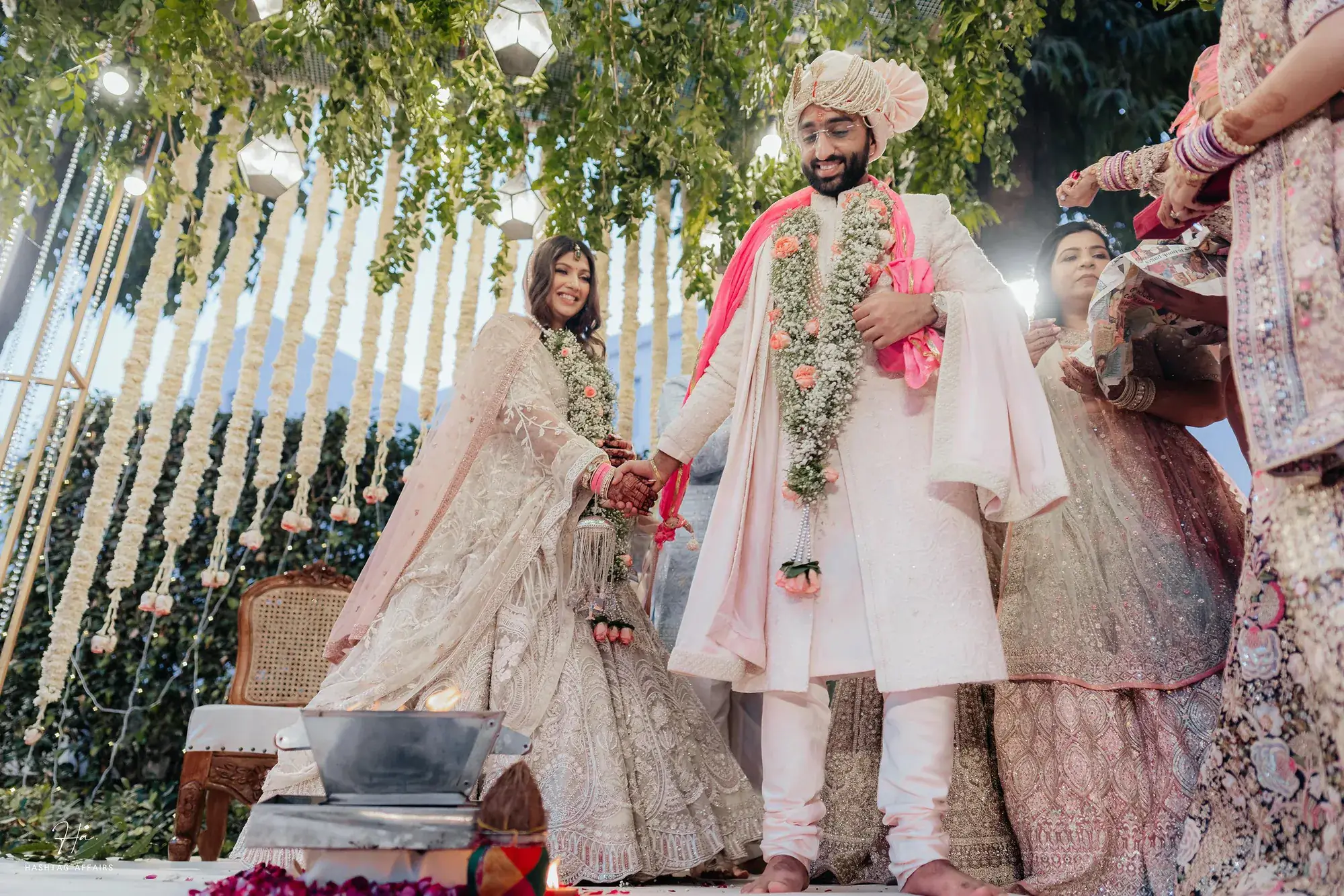 Bride and groom exchanging varmalas as their families celebrate around them