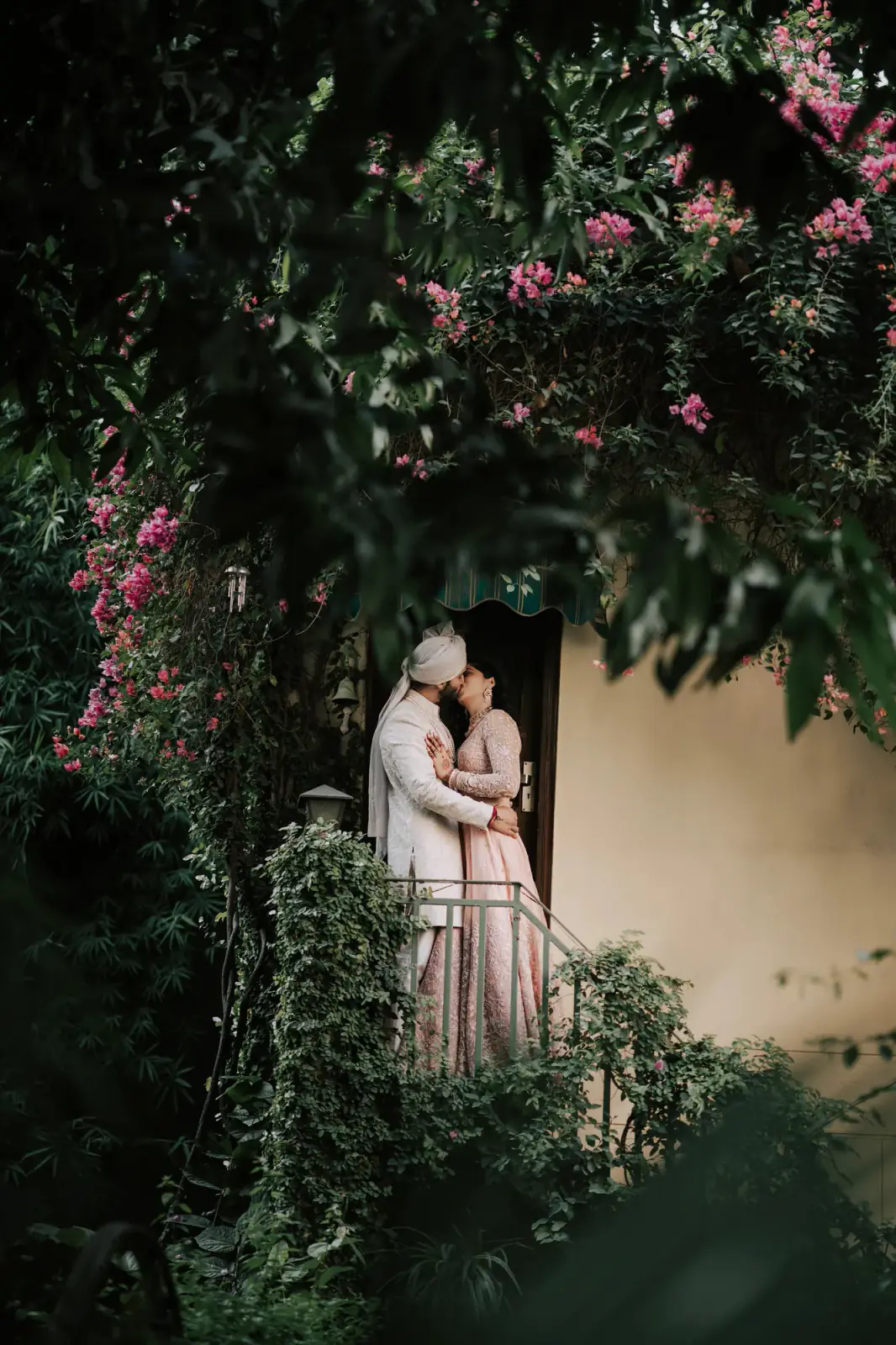 Couple embracing at a doorway framed by bougainvillea