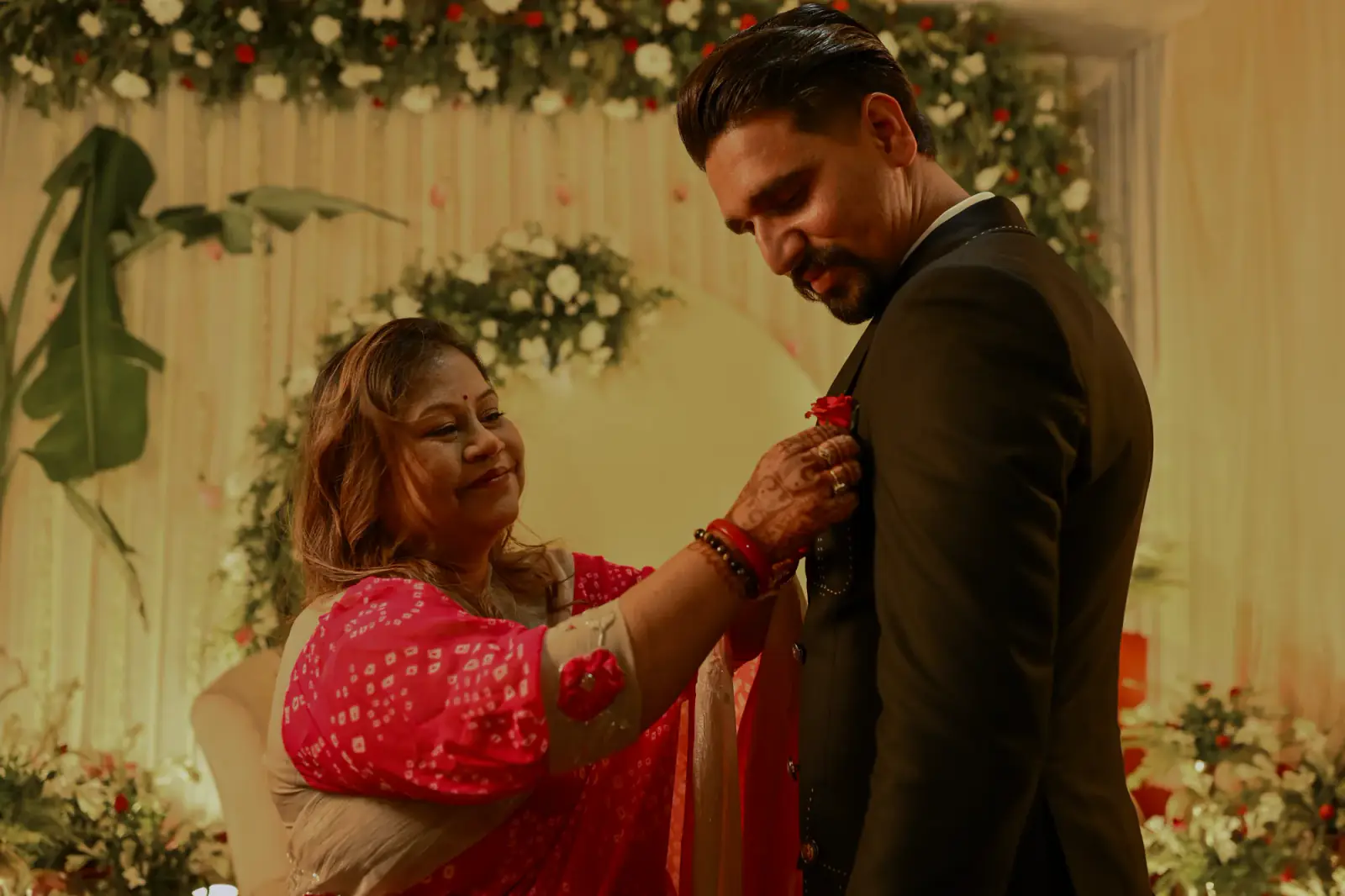 A relative smiling as she pins a rose to Sumit's lapel