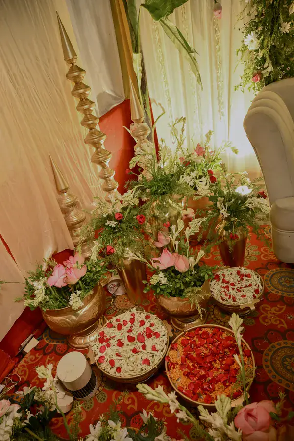 Lilies, brass and petal platters at the foot of the stage