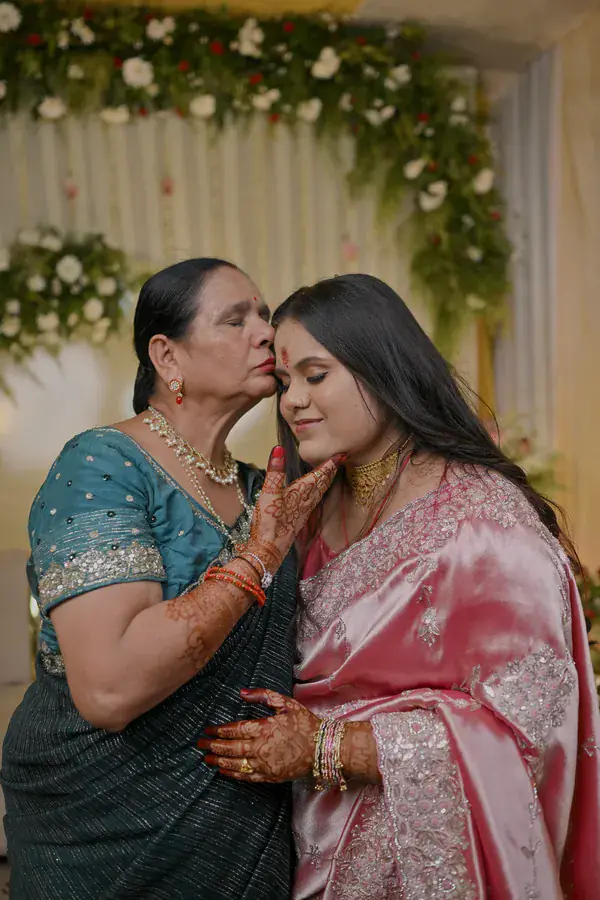 An elder of the family kissing Manisha's forehead