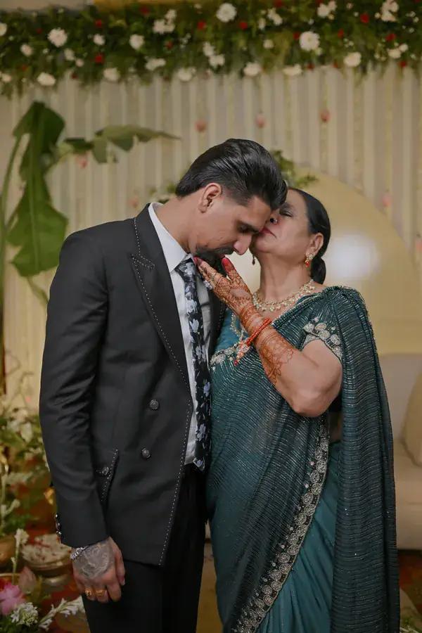 An elder kissing Sumit's cheek as he holds her hand