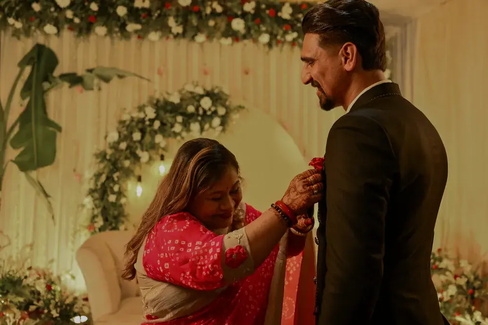 A relative pinning a rose to Sumit's lapel