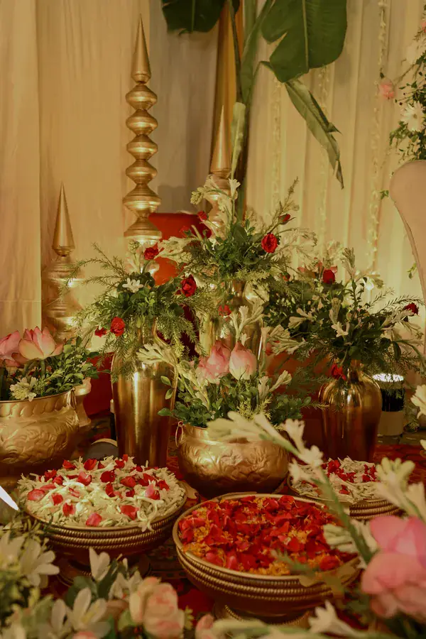 Brass urns of roses and lilies above platters of petals